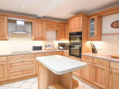 A kitchen with wooden cabinets a central island and built in appliances at The Old Lace Shop in Beer