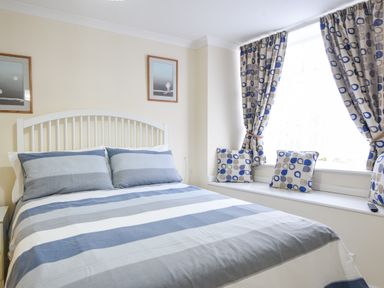 A bedroom with a bed near a window with curtains and cushions at The Old Lace Shop in Beer