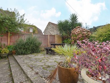 A garden patio area with potted plants tables and wooden fence at The Old Lace Shop in Beer