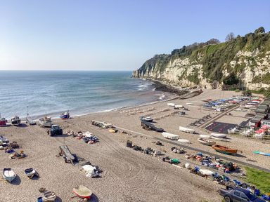 A pebble beach with boats trailers and equipment near cliffs by the sea at The Old Lace Shop in Beer