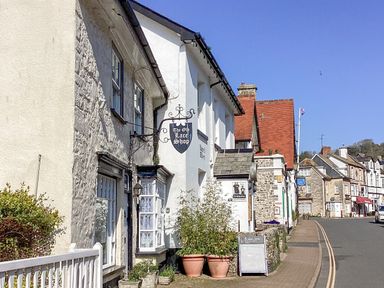 A street with old stone and brick buildings and a sign for The Old Lace Shop at The Old Lace Shop in Beer