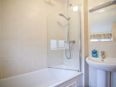 A bathroom with a bathtub shower combination and a sink with liquid soap at The Old Lace Shop in Beer