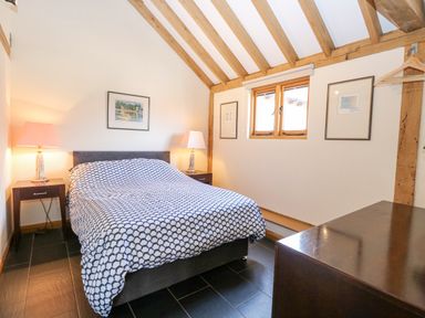 A bedroom with a double bed two bedside tables with lamps and framed pictures on the walls at 5a Hideaways in Hunstanton