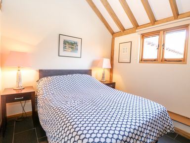 A bedroom with a bed covered in patterned bedding and two bedside tables with lamps at 5a Hideaways in Hunstanton