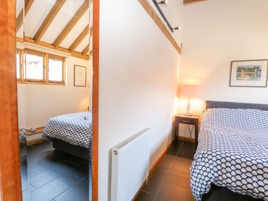 A bedroom with a bed covered by a patterned duvet a bedside table with a lamp a radiator and a wall mirror at 5a Hideaways in Hunstanton