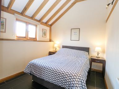 A bedroom with a double bed two bedside tables with lamps wooden ceiling beams and a window at 5a Hideaways in Hunstanton