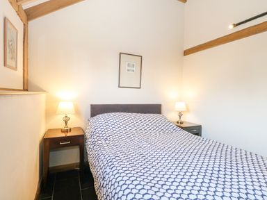 A bedroom with a double bed with patterned bedding and two bedside tables with lamps at 5a Hideaways in Hunstanton