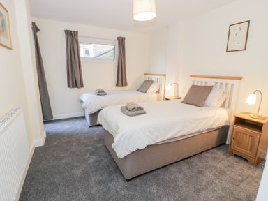 A bedroom with two single beds side by side with lamps on wooden bedside tables at Borthwen in Barmouth