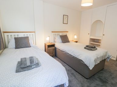 A bedroom with two single beds with bedside tables and lamps at Borthwen in Barmouth