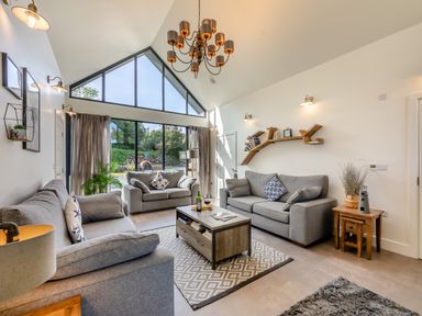 A living room with two gray sofas a coffee table and large windows at Shearwater Lodge in Bamburgh