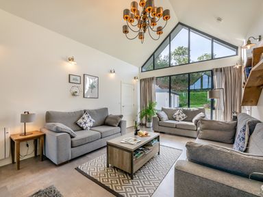 A living room with three grey sofas a coffee table and large windows at Shearwater Lodge in Bamburgh