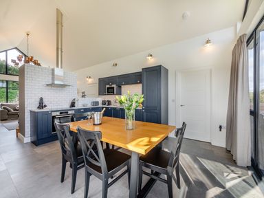 A kitchen with a wooden dining table and black chairs at Shearwater Lodge in Bamburgh