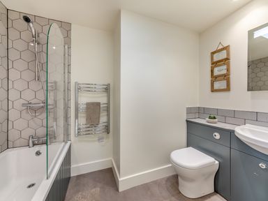 A bathroom with a bathtub shower combination and a toilet next to a sink at Shearwater Lodge in Bamburgh