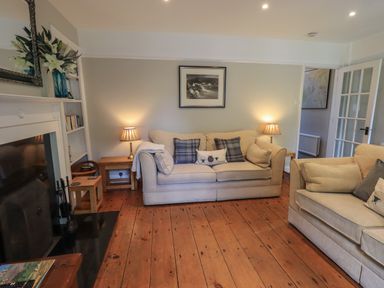 A living room with sofas pillows lamps a fireplace and wooden floors at Brook Cottage in Windermere