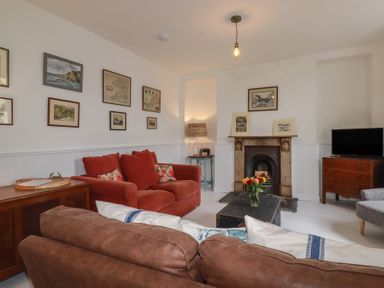 A living room with a sofa, fireplace and television at 84 Fore Street