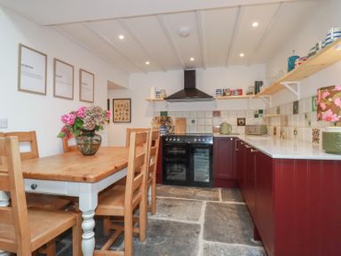 A kitchen with a dining table and wooden chairs at 84 Fore Street