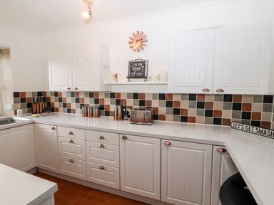A kitchen with white cabinets a tiled backsplash countertop kettle toaster and knives at Market Square Maisonette in Kirkby Lonsdale
