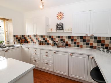 A kitchen with white cabinets and drawers a tiled backsplash and appliances at Market Square Maisonette in Kirkby Lonsdale