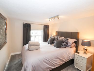 A bedroom with a bed with pillows towels bedside table and lamp at Market Square Maisonette in Kirkby Lonsdale