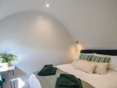 A bedroom with a double bed with green and cream pillows and folded towels on it at Maple in Wootton Fitzpaine near Charmouth