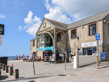 A stone building with a sign for Charmouth Heritage Coast Centre and people sitting outside near the sea at Maple in Wootton Fitzpaine near Charmouth