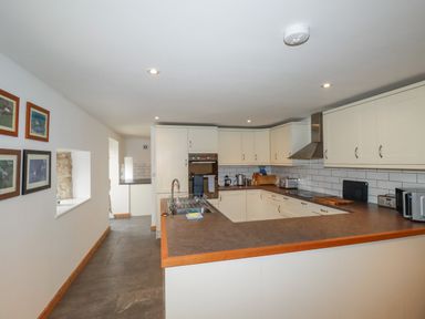 A kitchen with white cabinets and brown countertops at The Orchard in Cardinham