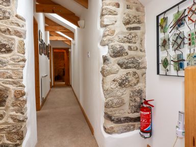 A hallway with stone walls wooden beams and a fire extinguisher at The Orchard in Cardinham
