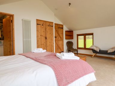 A bedroom with a bed covered with white sheets and a pink blanket at The Orchard in Cardinham