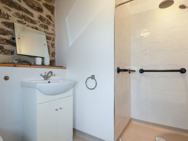 A bathroom with a sink cabinet mirror and a walk in shower with grab bars at The Orchard in Cardinham
