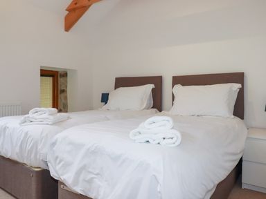 A bedroom with two single beds and folded towels on each bed at The Orchard in Cardinham