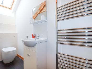 A bathroom with a toilet sink mirror and a chrome towel radiator at The Orchard in Cardinham