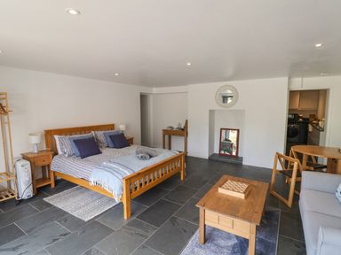 A bedroom with a wooden bed a coffee table with a chessboard and a small dining table at The Hideaway in Uplyme near Lyme Regis