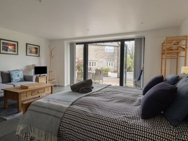 A bedroom with a bed and pillows a sofa a coffee table and a coat rack at The Hideaway in Uplyme near Lyme Regis