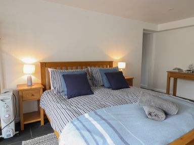 A bedroom with a wooden bed and blue patterned bedding at The Hideaway in Uplyme near Lyme Regis