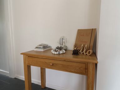 A wooden table with a stack of books seashell decor and a wooden hello sign at Rhode Hill Hideaway in Uplyme near Lyme Regis