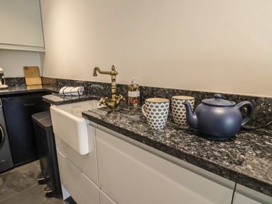 A kitchen countertop with a brass faucet two mugs and a teapot at The Hideaway in Uplyme near Lyme Regis