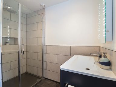 A bathroom with a glass shower enclosure and a sink with a soap dispenser at The Hideaway in Uplyme near Lyme Regis