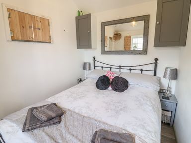 A bedroom with a bed pillows bedside tables lamps wall cabinets and a mirror at Chateau Petit in Trefeglwys