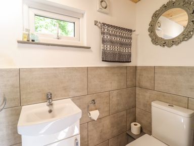 A bathroom with a sink mirror window towel and toilet at Chateau Petit in Trefeglwys