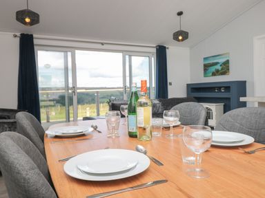 A dining table set with plates glasses and bottles in a room with sliding glass doors at Buttercup Lodge in Norton near Dartmouth