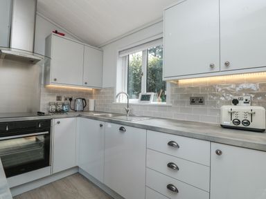 A kitchen with white cabinets a countertop a sink a toaster and a stove at Buttercup Lodge in Norton near Dartmouth