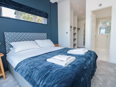 A bedroom with a bed a blue blanket two bedside tables and an ensuite bathroom at Buttercup Lodge in Norton near Dartmouth