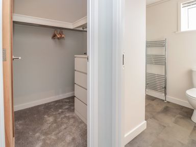 A walk-in closet with hangers and drawers next to a bathroom with a radiator and toilet at Primrose Lodge in Norton near Dartmouth