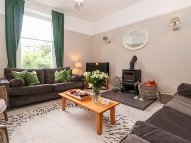 A living room with sofas a coffee table and a wood stove at Church View in Grange-Over-Sands