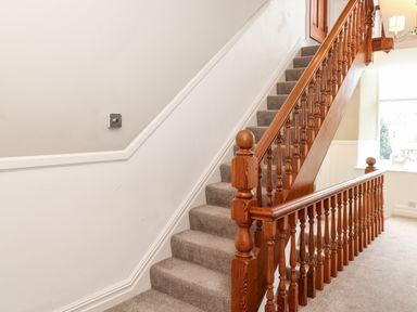 A carpeted staircase with wooden banisters and a window at Church View in Grange-Over-Sands