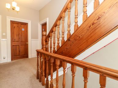 A staircase with wooden balusters and two wooden doors in a hallway at Church View in Grange-Over-Sands