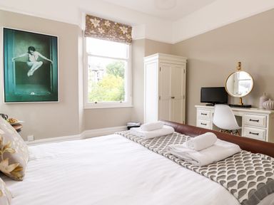 A bedroom with a bed towels wardrobe desk chair mirror and a window at Church View in Grange-Over-Sands