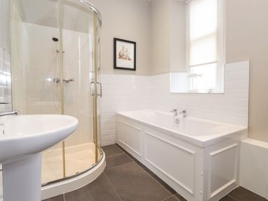 A bathroom with a shower cabin a bathtub a sink and a window at Church View in Grange-Over-Sands