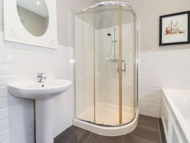 A bathroom with a pedestal sink a glass enclosed shower and a bathtub at Church View in Grange-Over-Sands