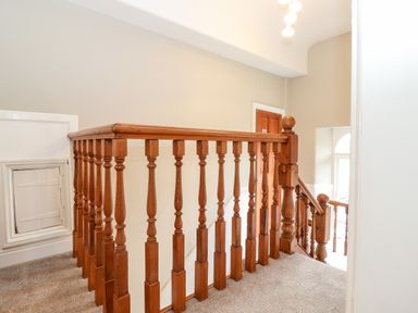 A stair landing with wooden balustrades beige walls and carpet at Church View in Grange-Over-Sands